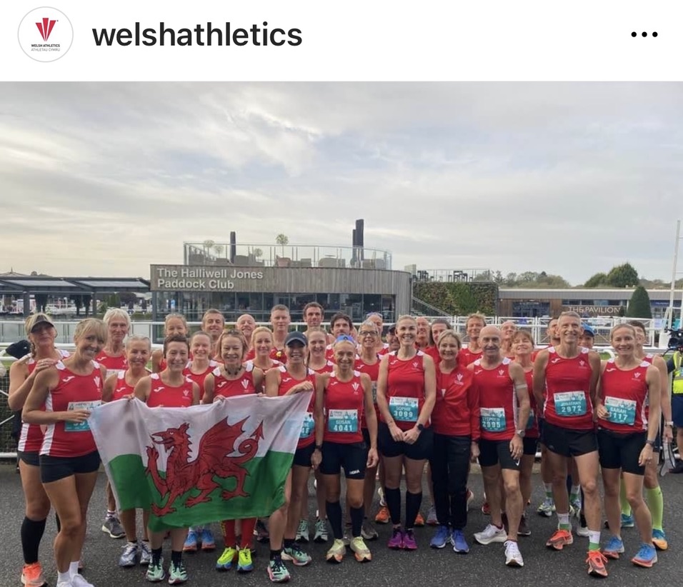 Welsh Masters runners in red Wales vests posing together with a Welsh flag at the 2023 Chester Marathon